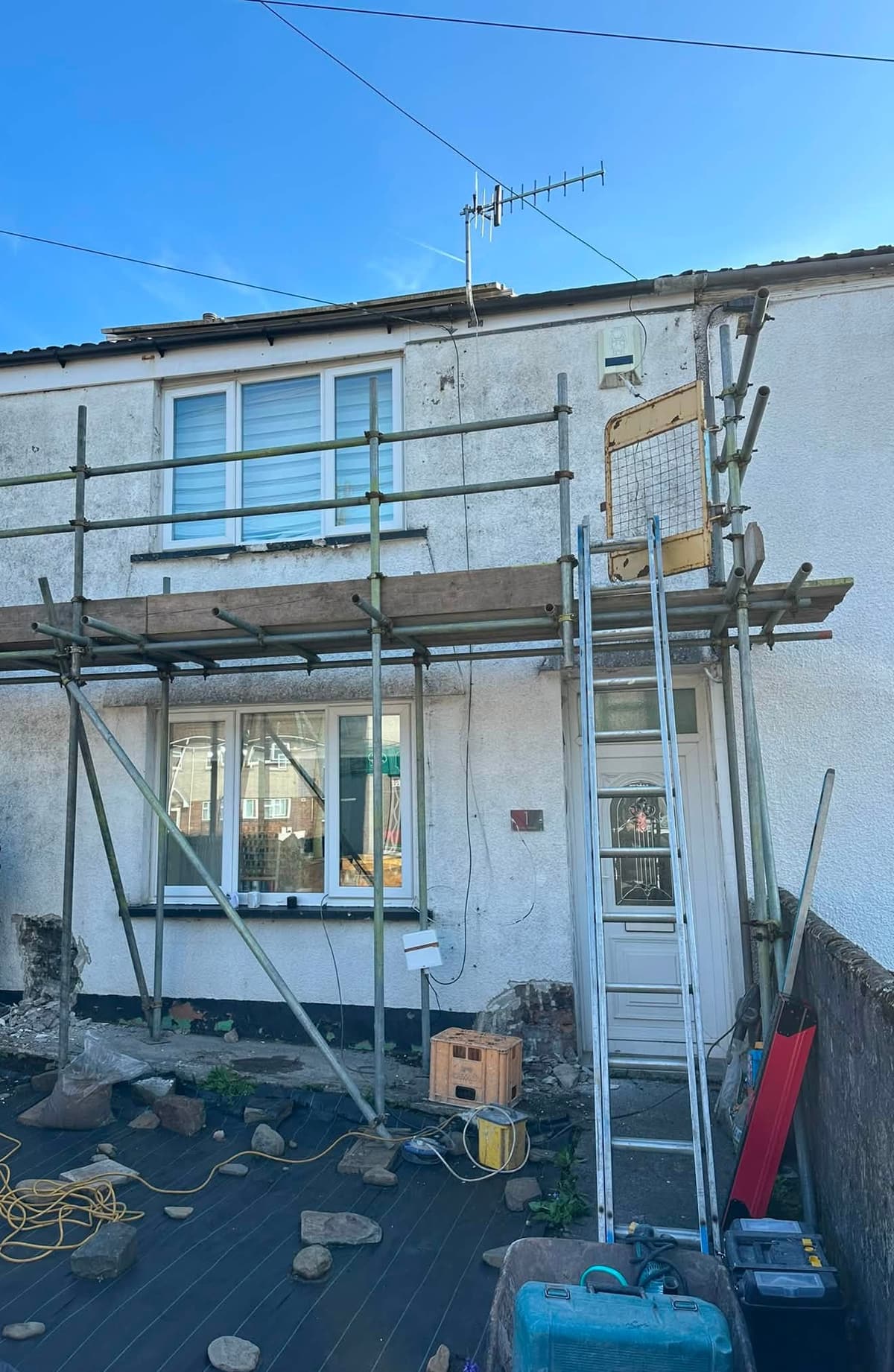 Before: front of a two-storey house, scaffolded with weathered walls, then finished in fresh white render with new windows