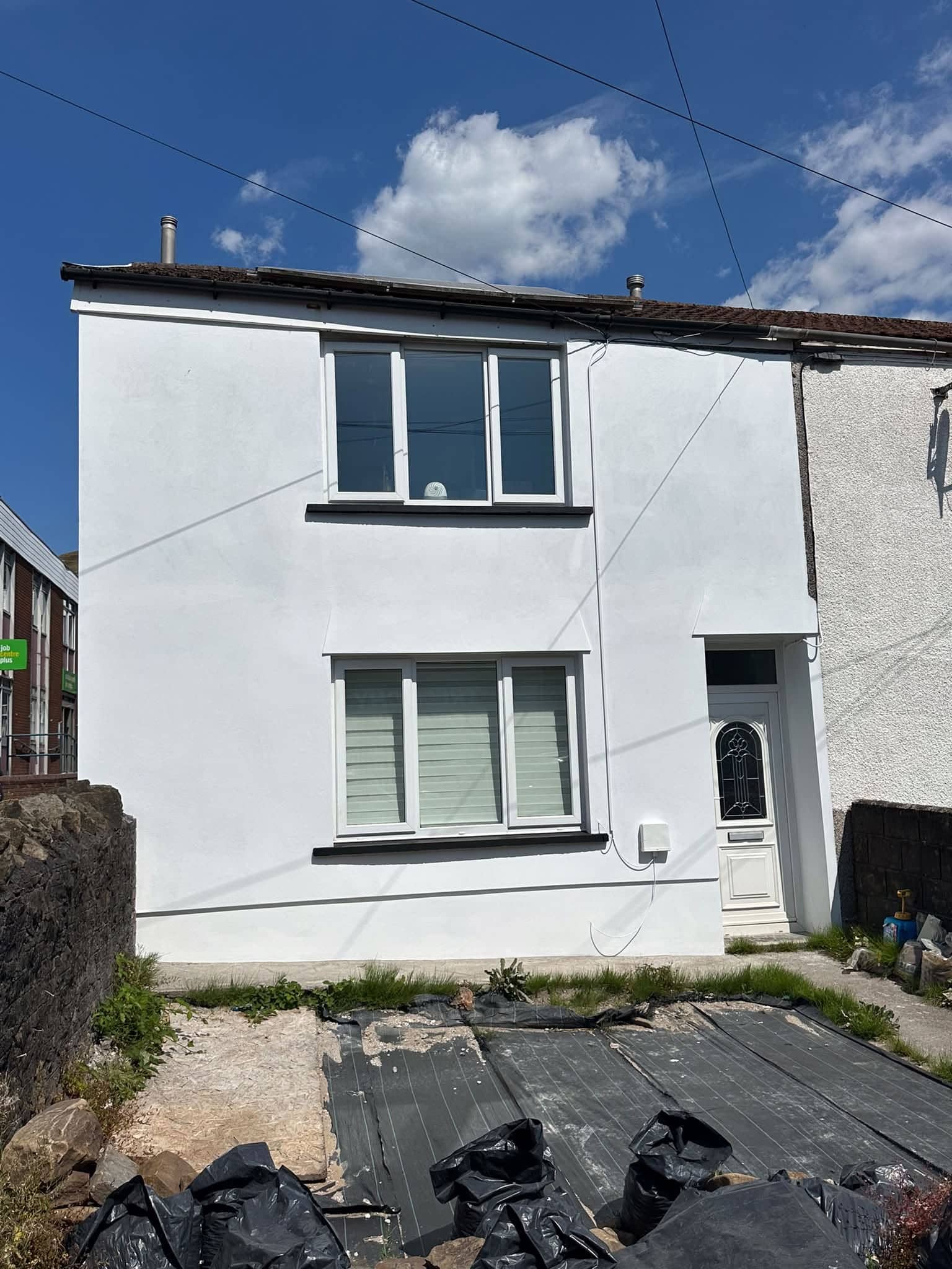 Fully renovated house exterior by C Thomas Building Services — fresh white render and new windows